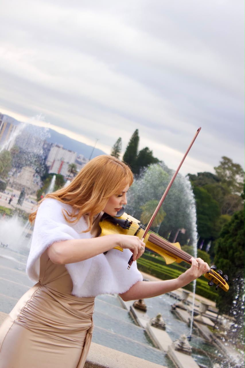 Mileidy tocando violino ao lado do chafariz